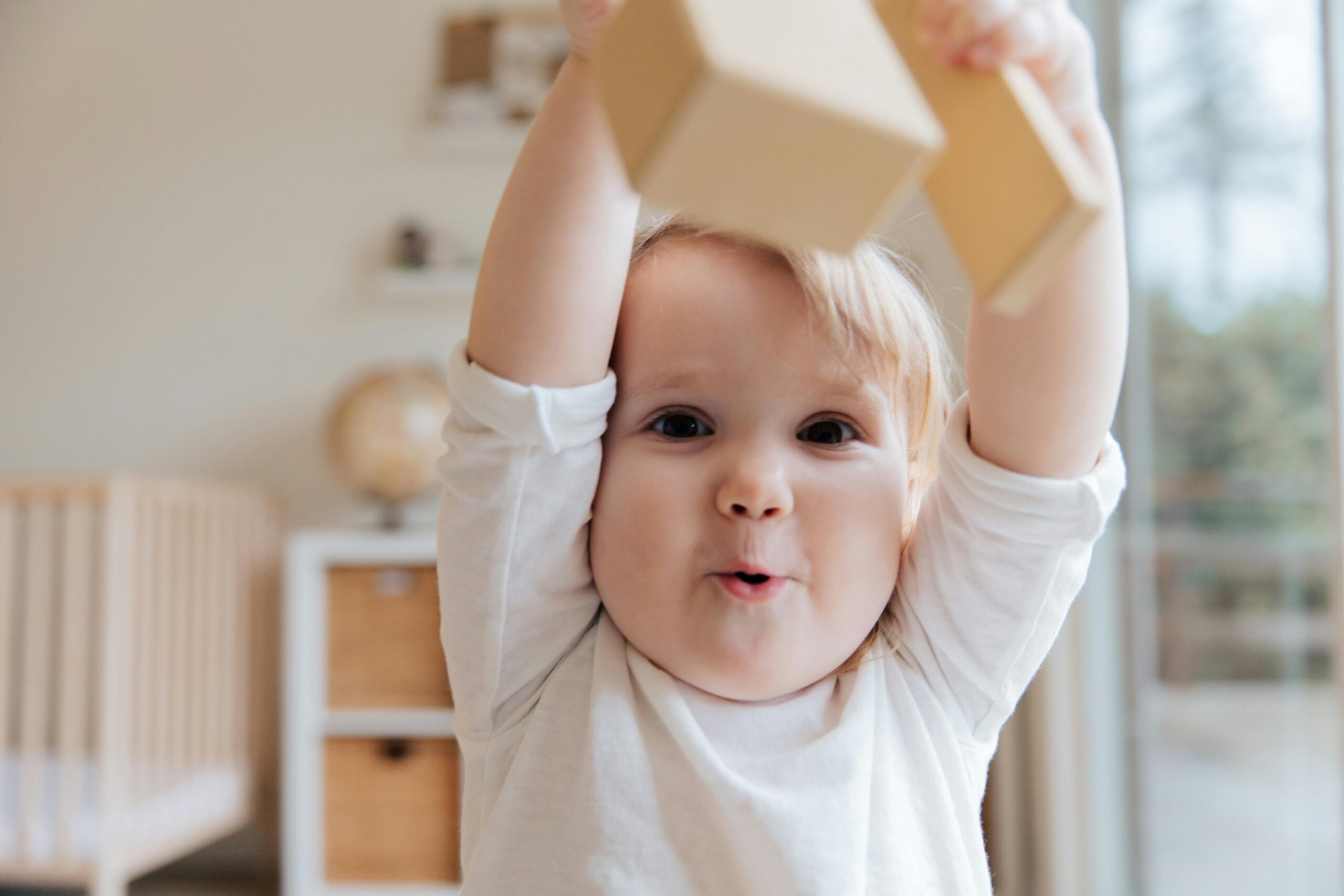Home Adorable baby enjoying playtime with wooden blocks in a cozy indoor setting. Perfect depiction of joy and learning.